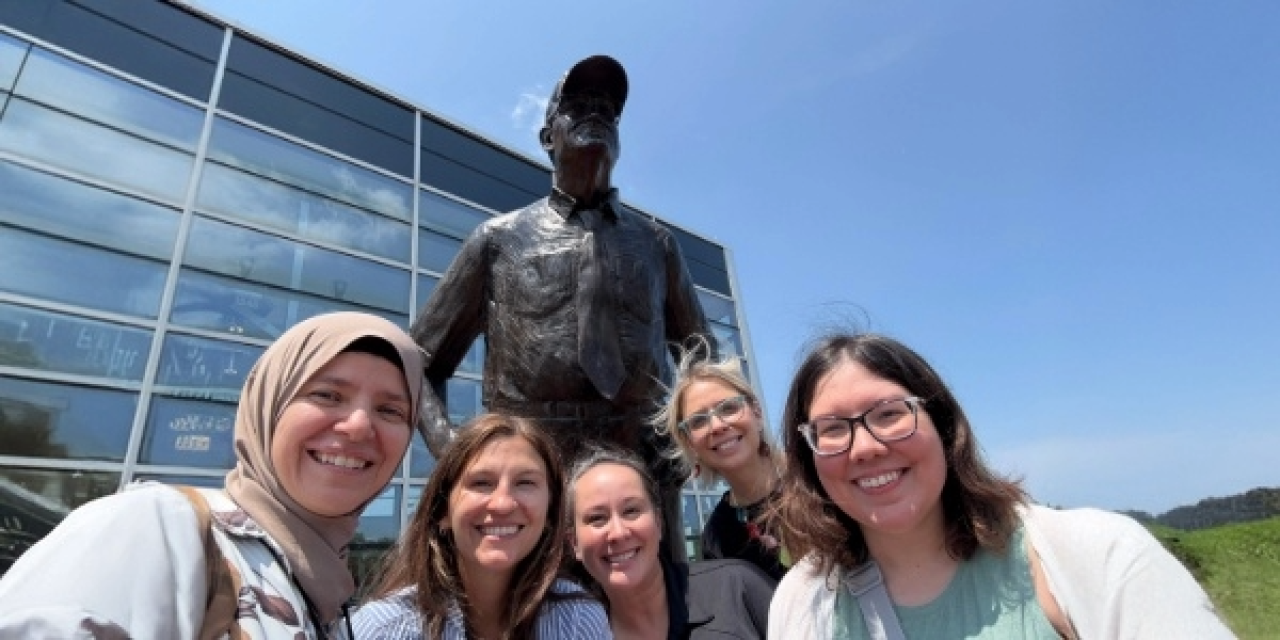 Five staff members posing with a statue and smiling